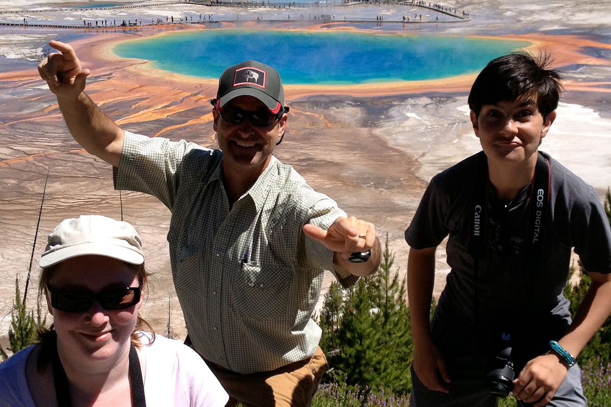 Smiling Private Tour Guests at Yellowstone’s Grand Prismatic Spring - Buffalo Roam Tours