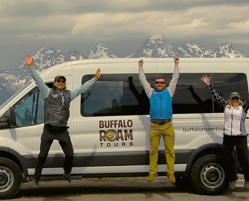 Buffalo Roam Tours guides celebrating in front of the Grand Teton mountains, representing a Grand Teton National Park travel guide experience in Jackson Hole.